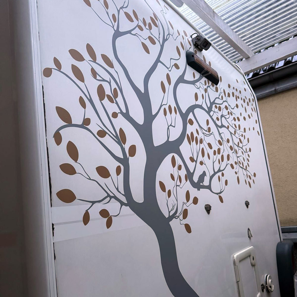 Zweifarbiger großer Baum mit Vögeln an der Rückwand eines Wohnmobils