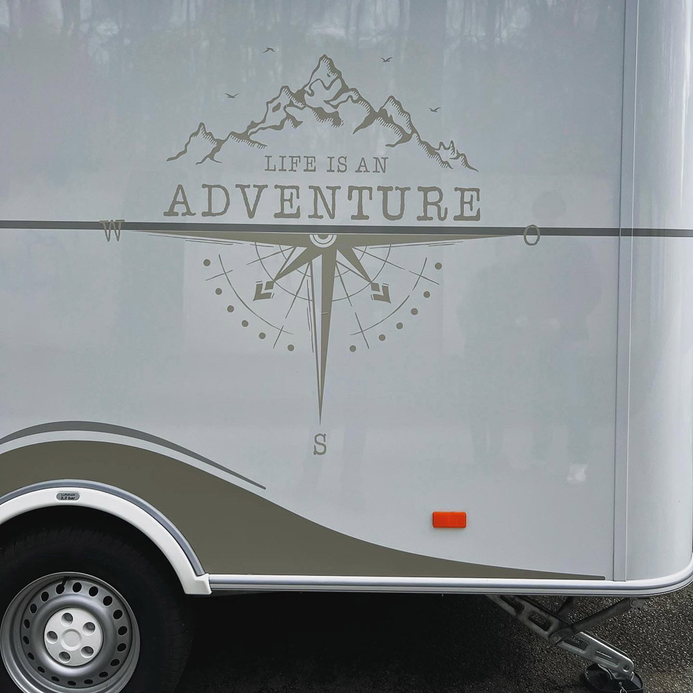 Life is an Adventure mit Bergen und Kompass an einer Wohnmobilseitenwand
