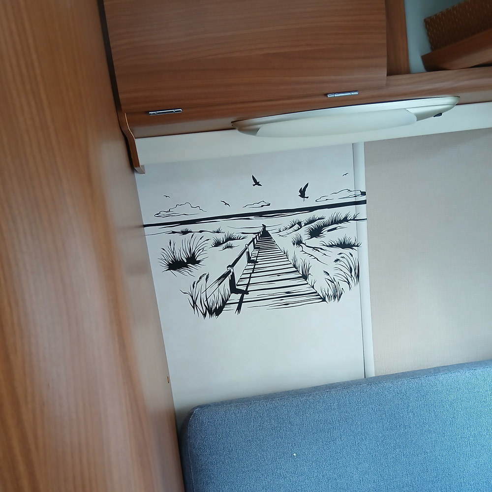 Steg durch die Dünen an einer Innenwand neben der Sitzbank im Camper