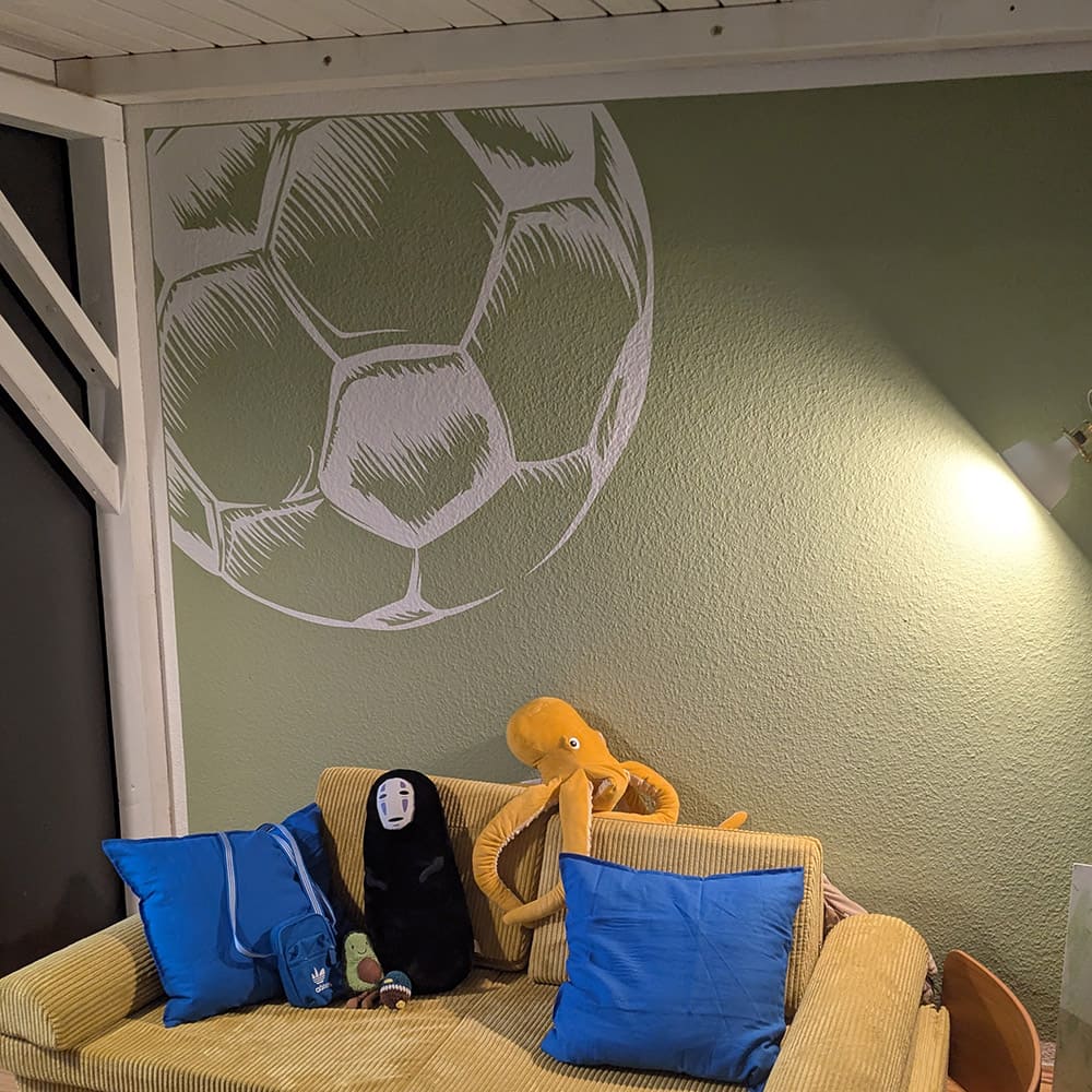 Weiße Wandtattoo-Fußball-Ecke an einer grünen Kinderzimmerwand unter einem Hochbett