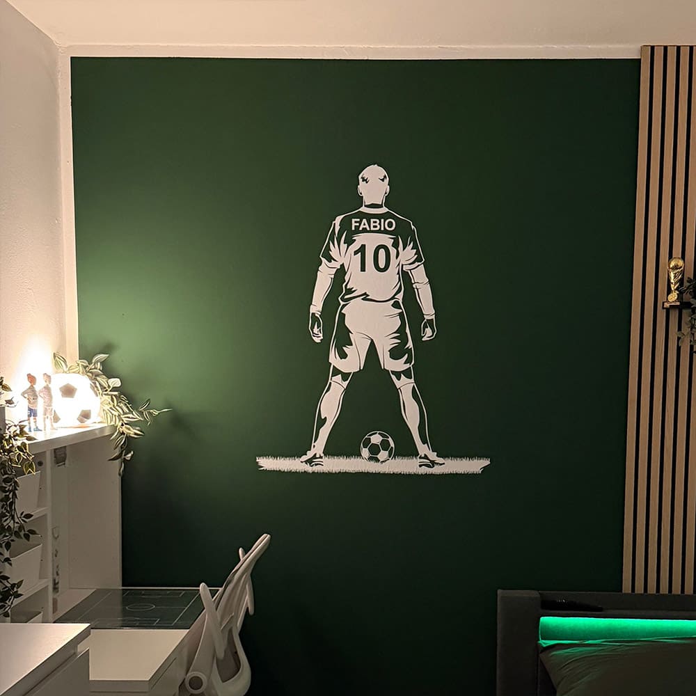 Weißer Wandtattoo-Fußballspieler mit persönlichem Namen und Rückennummer auf grüner Wand