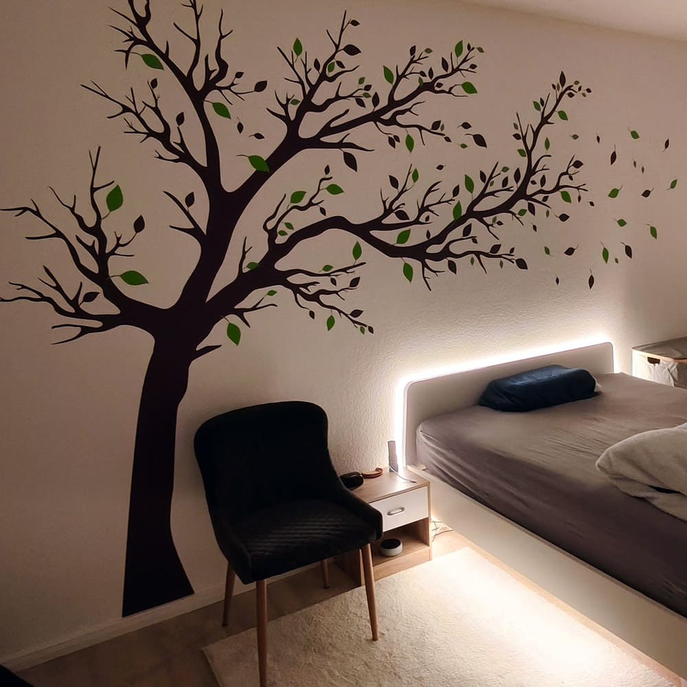 Großer Wandtattoo-Baum mit schwarzen Ästen und grünen Blättern im Schlafzimmer