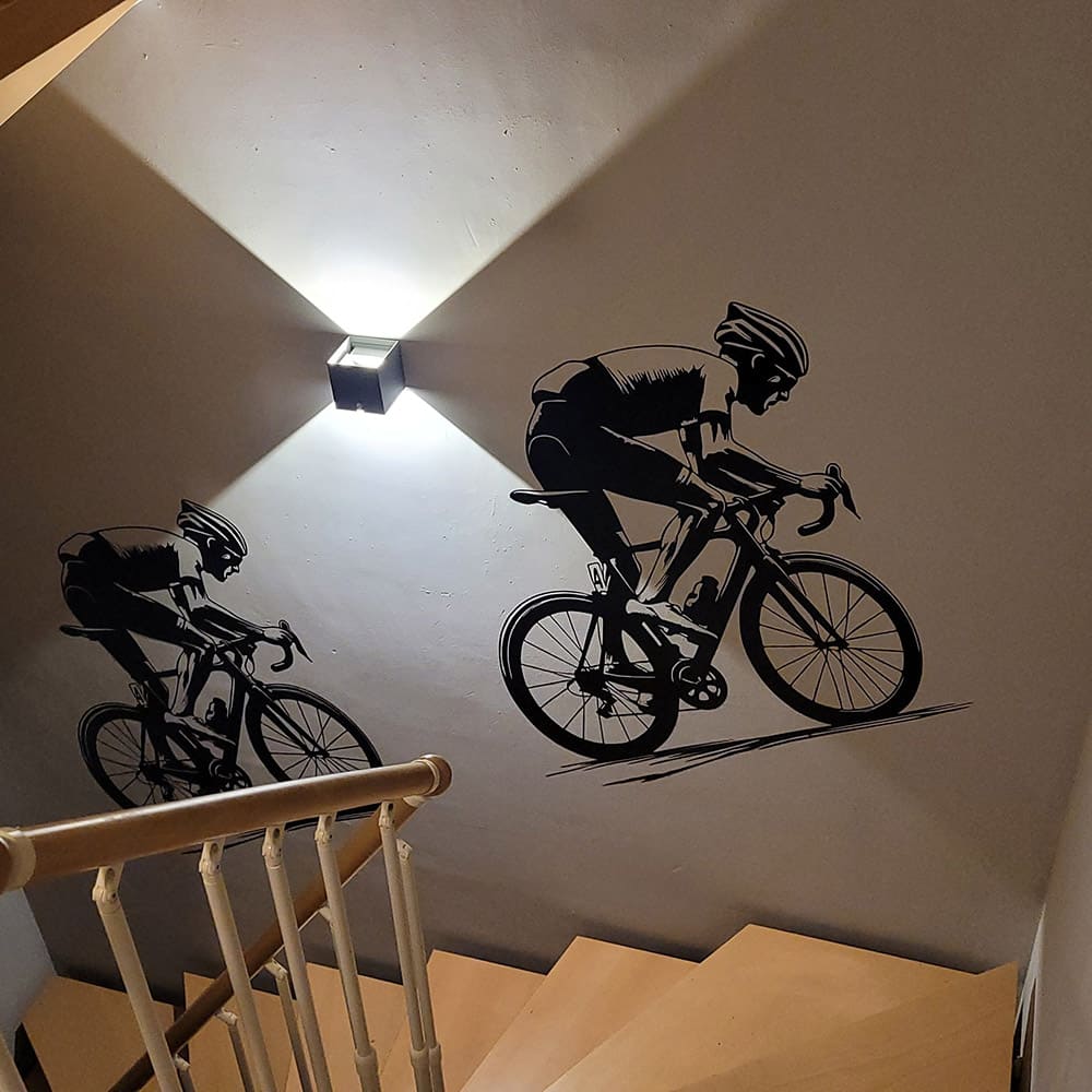 Zwei schwarze Wandtattoo-Radrennfahrer in verschiedenen Größen an einer Treppenwand