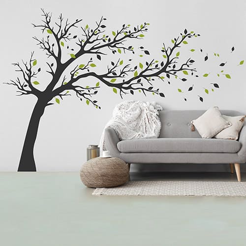 Baum-Wandtattoo mit wehenden Blättern neben einem grauen Sofa